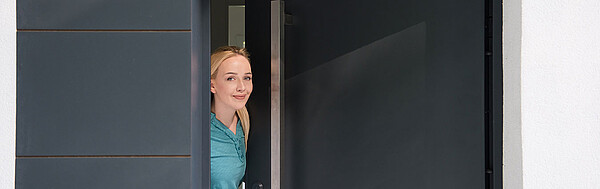 eine blonde, junge Frau öffnet die Haustüre